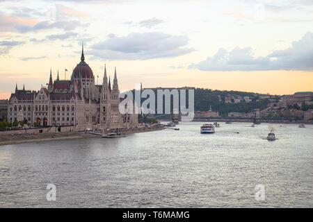 Hungarian Parliament at sunset with boats cruising in the danube river. Stock Photo