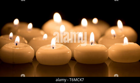 White candles on a black reflecting background Stock Photo