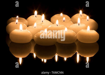 White candles on a black reflecting background Stock Photo