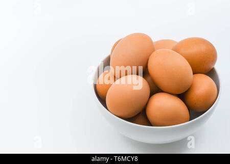 Close up of fresh eggs in a white bowl against a plain white background Stock Photo