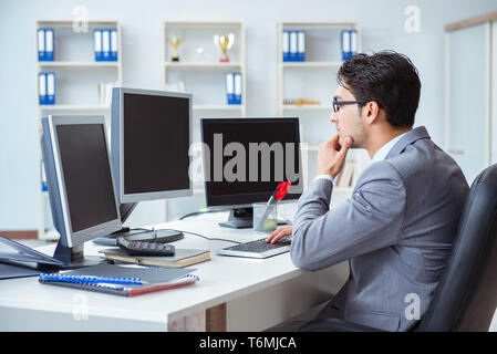 Businessman sitting in front of many screens Stock Photo
