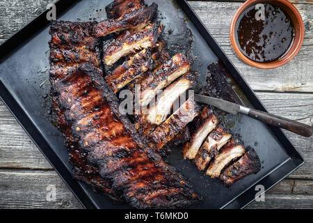 Barbecue spare ribs St Louis cut with hot honey chili marinade as top view in a rustic skillet Stock Photo