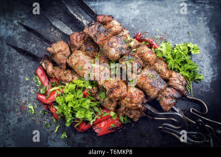 Traditional Russian shashlik on a barbecue skewer with paprika as closeup on an old board Stock Photo