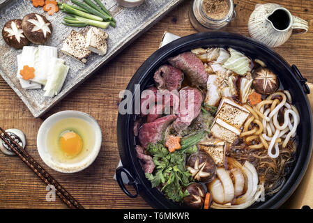 Traditional Sukiyaki pot with Kobe Beef and Vegetable as close-up on wooden table Stock Photo