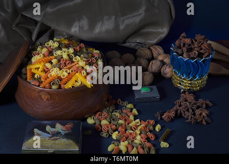 Colorful paste in a wooden bowl and a blue and yellow glass bowl containing star anise. Nuts and star anise and two porcelain boxes on  the floor. Stock Photo
