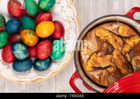 Traditional artisan bread in baking pan and Easter painted eggs.