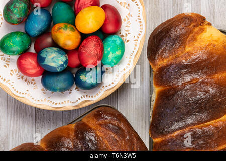 Traditional sweet bread in baking pan and Easter painted eggs, top view. Stock Photo