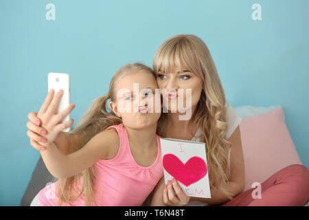 Cute little girl and her mother taking selfie with handmade card at home Stock Photo