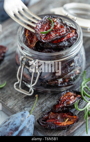 Spicy dried plum in a jar and a fork close-up. Stock Photo