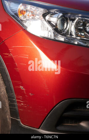 Scratched paint on red  modern car bumper close up view Stock Photo
