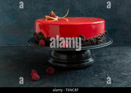Modern mousse cake with red glaze and raspberry. Stock Photo