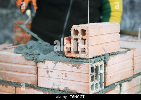 Industrial bricklayer installing bricks on construction site Stock Photo