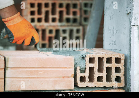 Industrial bricklayer installing bricks on construction site Stock Photo