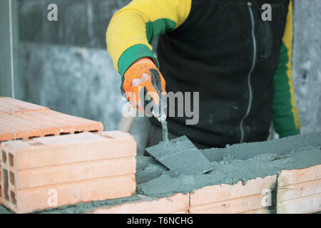 Industrial bricklayer installing bricks on construction site Stock Photo