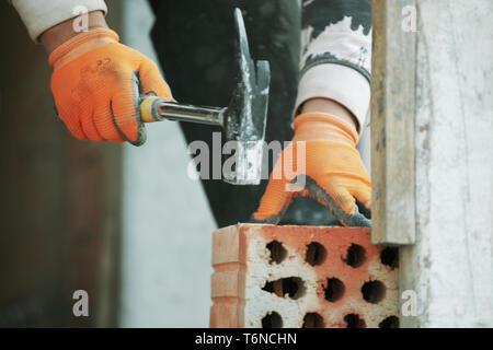 Industrial bricklayer installing bricks on construction site Stock Photo