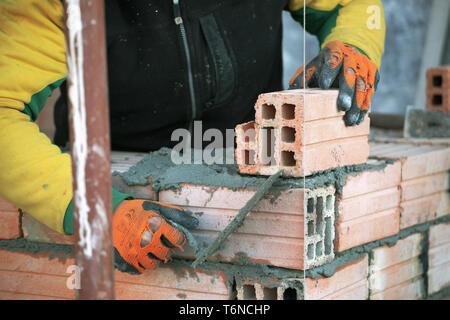 Industrial bricklayer installing bricks on construction site Stock Photo