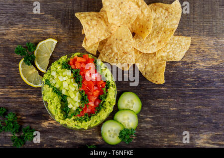 Guacamole with corn chips and salsa on rustic wooden table Stock Photo