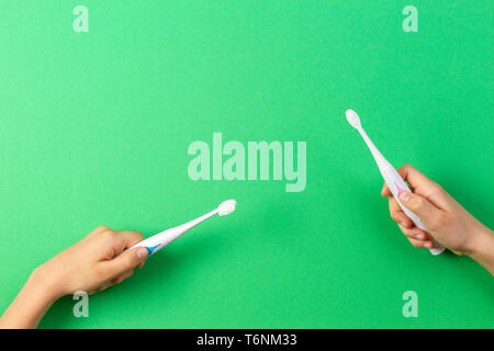 Kid hands with electric toothbrushes on green background Stock Photo
