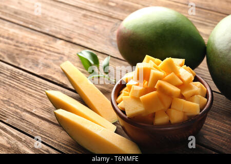 Whole and cut mangoes on wooden background Stock Photo