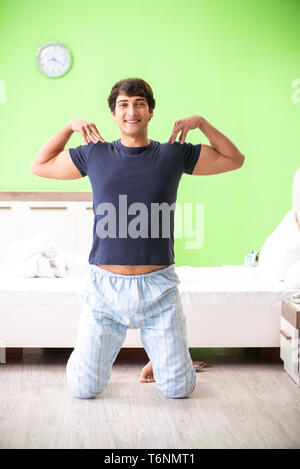 The young man in pajamas doing morning exercises Stock Photo