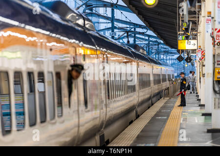 Utsunomiya, Japan - April 5, 2019: Train station platform with shinkansen and conductor looking out window at night evening Stock Photo