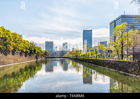 Tokyo, Japan - April 1, 2019: Reflection in pool by Imperial palace during spring day with cityscape skyscrapers in downtown park Stock Photo