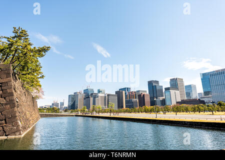 Tokyo, Japan - April 1, 2019: Moat water by Imperial palace during spring day with cityscape skyscrapers in downtown park Stock Photo