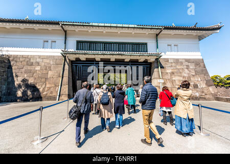 Tokyo, Japan - April 1, 2019: Park with people tourists walking entering gate to Imperial palace during spring day in downtown Stock Photo