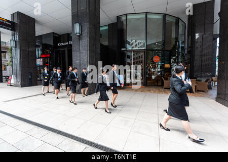 Tokyo, Japan - April 1, 2018: Kyobashi Edogrand modern business center building with architecture entrance and many young women businesswomen walking  Stock Photo