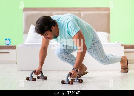 Young man in pajamas doing morning exercises Stock Photo