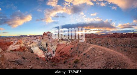 Colorful, red orange rock formations at sunset with colored clouds, hiking trail, White Dome, sandstone rocks, Valley of Fire State Park, Mojave Stock Photo