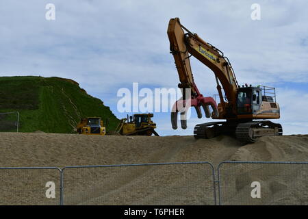 West Bay, Dorset, UK. 2nd May 2019. A large coastal defence is underway at West Bay in Dorset. Large blocks are delivered by boats and off loaded into the sea front by bucket loads. The stones come from Scotland where its picked up by large mechanical clasps and driven up the pebble beach. The sea front is where the TV show Broadchurch was filmed.Picture Credit: Robert Timoney/Alamy Live Newss Stock Photo