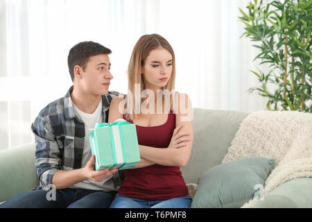 Offended young woman refusing to take gift from her boyfriend at home Stock Photo