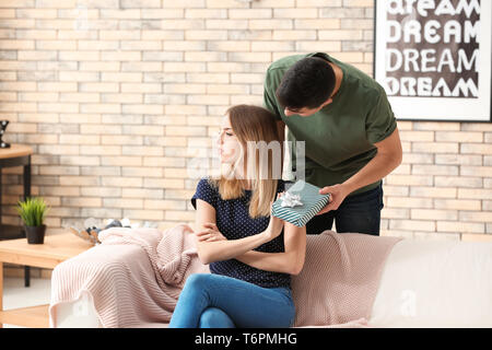 Offended young woman refusing to take gift from her boyfriend at home Stock Photo