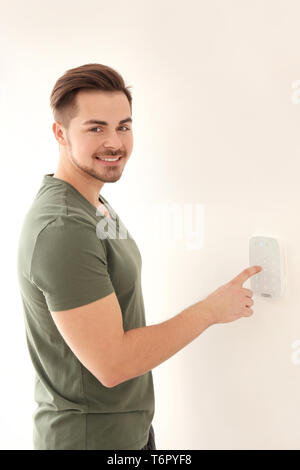 Young man entering code on security alarm system, indoors Stock Photo