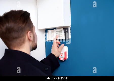 Young man entering code on security alarm system, indoors Stock Photo