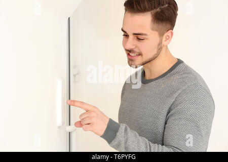 Young man entering code on security alarm system, indoors Stock Photo