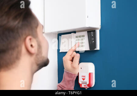 Young man entering code on security alarm system, indoors Stock Photo