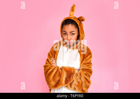Young woman in bunny kigurumi standing isolated on pink background crossed arms looking camera upset Stock Photo