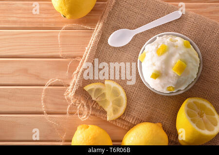 Lemon ice cream cup decorated with lemon segments on a wooden table. Horizontal composition. Top view. Stock Photo
