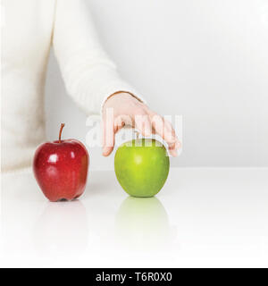 Green and Red apple on white table. Hand touching  green and red apple on the white table. isolated on white. Stock Photo