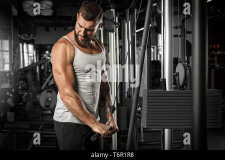 Bearded man bodybuilder standing exercising at gym doing cable straight arm pulldown smiling proud Stock Photo