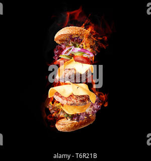 burning and flying burger, a double cheeseburger with two succulent beef cutlets and cheese cheddar on a black background. studio light Stock Photo
