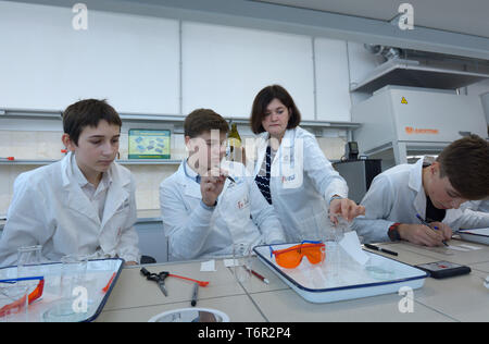 At a school chemistry lab. Female teacher conducting lesson of chemistry   for pupils wearing lab coats. Kiev, Ukraine. November 28, 2018 Stock Photo