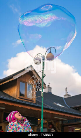 Girl looking at giant soap bubble Stock Photo