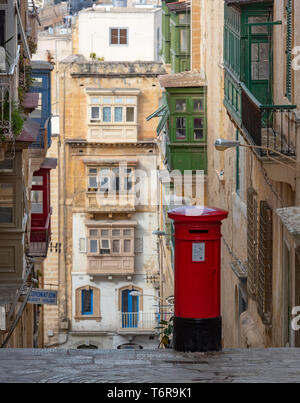 Remnants of a previous age; a bright red British era post box contrasts with the muted, colours of the galleriji in Mikiel Anton Vassalli Street Stock Photo