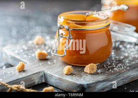 Salted caramel and a spoon in a glass jar. Stock Photo