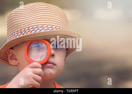 Cute little boy holding magnifying glass Stock Photo