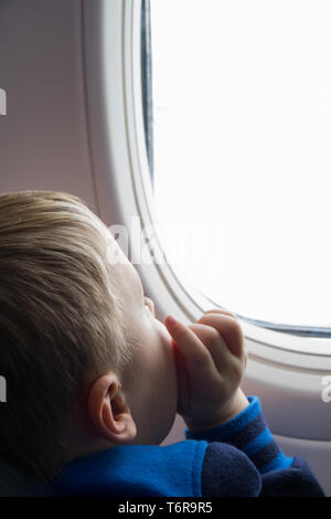 Little boy looking through the plane window Stock Photo