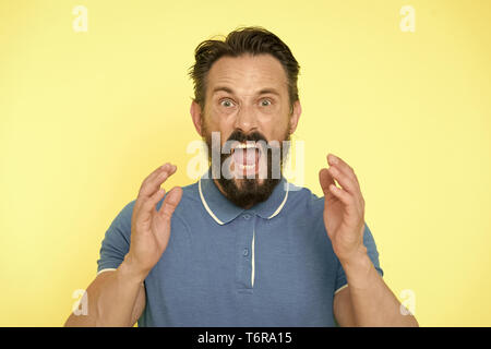 Overwhelmed with emotions. Handsome shouting mature man screaming standing against yellow background. Man bearded irritated annoyed can not keep calm anymore. Stop annoying him. Stressful adult life. Stock Photo